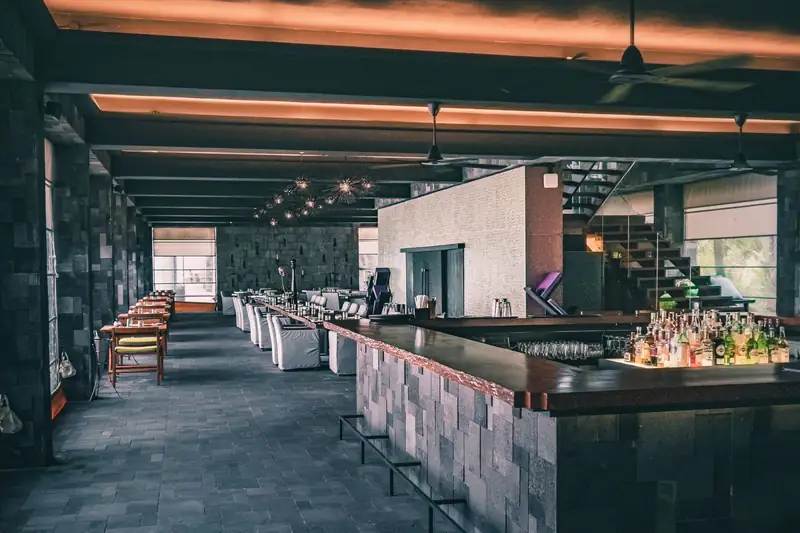 Enterijer restorana sa dugim šankom i barskim stolicama